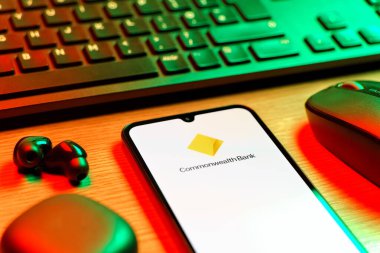Prag, Çek Cumhuriyeti - 08 12 2025: Commonwealth Bank logosunu gösteren klavyesi ve cep telefonu olan bir masanın yan görüntüsü. Commonwealth Bank, Avustralya 'da finansal hizmetler sağlayan bir bankadır..
