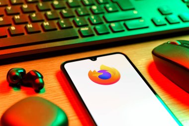 Prag, Çek Cumhuriyeti - 08 12 2025: Firefox logosunu gösteren klavyesi ve cep telefonu olan bir masanın yan görüntüsü. Firefox hızlı ve güvenli internet taraması için bir web tarayıcısıdır.