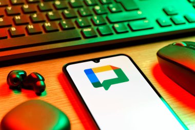 Prag, Çek Cumhuriyeti - 08 12 2025: Google Chat logosunu gösteren klavyesi ve cep telefonu olan bir masanın yan görüntüsü. Google Chat mesajlaşma ve takım işbirliği için bir platformdur.
