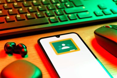 Prag, Çek Cumhuriyeti - 08 12 2025: Google Sınıfı logosunu gösteren klavyesi ve cep telefonu olan bir masanın yan görüntüsü. Google Sınıfı, sınıfları ve eğitim içeriğini yönetmek için bir platformdur.