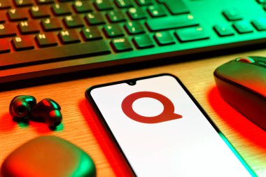 Prag, Çek Cumhuriyeti - 08 12 2025: Quora logosunu gösteren klavyesi ve cep telefonu olan bir masanın yan görüntüsü. Quora soru sormak ve bilgi paylaşmak için bir platformdur..