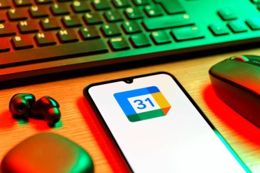 Prag, Çek Cumhuriyeti - 08 12 2025: Google Takvim logosunu gösteren klavyesi ve cep telefonu olan bir masanın yan görüntüsü. Google Takvimi olayları zamanlamak ve yönetmek için bir platformdur.