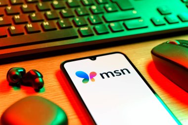 Prag, Çek Cumhuriyeti - 08 12 2025: MSN logosunu gösteren klavyesi ve cep telefonu olan bir masanın yan görüntüsü. MSN haber, e-posta ve çevrimiçi hizmetler için bir platformdur.