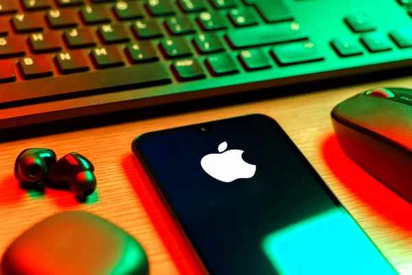 Prag, Çek Cumhuriyeti - 08 12 2025: Apple logosunu gösteren klavyesi ve cep telefonu olan bir masanın yan görüntüsü. Apple iPhone, bilgisayar ve hizmet üreten bir teknoloji şirketidir..