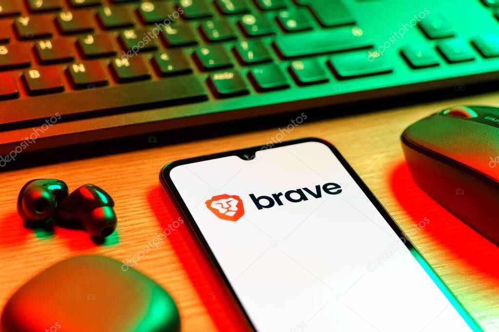Prague, Czechia - 08 12 2025: A side view of a desk with a keyboard and a mobile phone displaying the Brave logo. Brave is a web browser focused on privacy and speed.