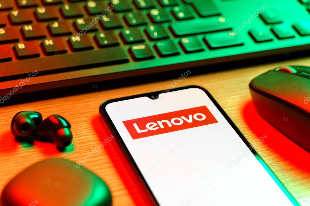 Prague, Czechia - 08 12 2025: A side view of a desk with a keyboard and a mobile phone displaying the Lenovo logo. Lenovo is a technology company producing computers and electronics.
