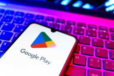 Prag, Çek Cumhuriyeti - 08 19 2025: Google Play logosunu gösteren klavyenin üzerinde duran bir cep telefonunun yakından görüntüsü. Google Play uygulamaları, oyunları ve dijital içeriği indirmek için bir platformdur.