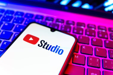 Prag, Çek Cumhuriyeti - 08 19 2025: Youtube Stüdyo logosunu gösteren klavyenin üzerinde duran cep telefonunun yakından görüntüsü. Youtube Studio YouTube kanallarını yönetmek ve analiz etmek için bir platformdur.