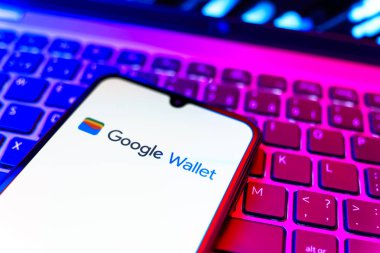 Prag, Çek Cumhuriyeti - 08 19 2025: Google Cüzdan logosunu gösteren klavyenin üzerinde duran cep telefonunun yakından görüntüsü. Google Cüzdanı dijital ödeme yöntemlerini depolamak ve kullanmak için bir platformdur.