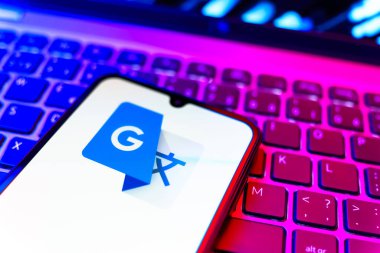 Prag, Çek Cumhuriyeti - 08 19 2025: Google Translate logosunu gösteren klavyenin üzerinde duran cep telefonunun yakından görüntüsü. Google Çevirisi metni ve konuşmayı diller arası çevirmek için bir platformdur..