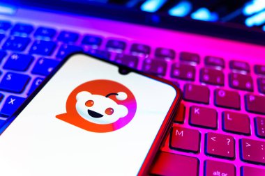 Prag, Çek Cumhuriyeti - 08 19 2025: Bir klavyenin üzerinde duran ve Reddit logosunu gösteren cep telefonunun yakından görüntüsü. Reddit tartışma, haber ve toplum içeriği için bir platformdur.
