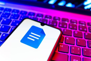 Prag, Çek Cumhuriyeti - 08 19 2025: Google Docs logosunu gösteren klavyenin üzerinde duran cep telefonunun yakından görüntüsü. Google Docs metin belgeleri oluşturmak ve düzenlemek için bir platformdur.