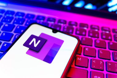 Prag, Çek Cumhuriyeti - 08 19 2025: Klavyede duran ve Microsoft OneNote logosunu gösteren bir cep telefonunun yakından görüntüsü. Microsoft OneNote not almak ve düzenlemek için bir platformdur.