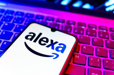 Prag, Çek Cumhuriyeti - 08 19 2025: Klavyenin üzerinde Alexa logosunu gösteren cep telefonunun yakın çekim görüntüsü. Alexa akıllı aygıtlar ve servisler için ses asistanıdır.