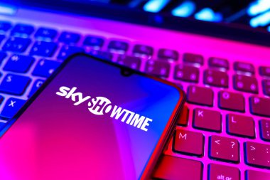 Prag, Çek Cumhuriyeti - 08 19 2025: SkyShowtime logosunu gösteren klavyenin üzerinde duran cep telefonunun yakından görüntüsü. SkyShowtime, sinema ve televizyon dizileri için bir yayın platformudur..