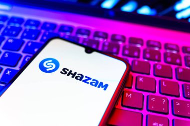 Prag, Çek Cumhuriyeti - 08 19 2025: Klavyede duran ve Shazam logosunu gösteren bir cep telefonunun yakından görüntüsü. Shazam şarkıları ve müzik parçalarını tanımlamak için bir uygulamadır.