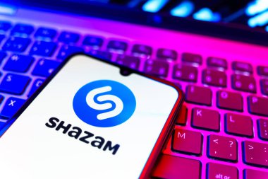 Prag, Çek Cumhuriyeti - 08 19 2025: Klavyede duran ve Shazam logosunu gösteren bir cep telefonunun yakından görüntüsü. Shazam şarkıları ve müzik parçalarını tanımlamak için bir uygulamadır.