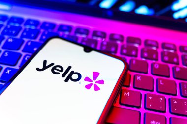 Prag, Çek Cumhuriyeti - 08 19 2025: Klavyede duran ve Yelp logosunu gösteren bir cep telefonunun yakından görüntüsü. Yelp yerel işletmeleri bulmak ve incelemek için bir platformdur.