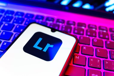 Prag, Çek Cumhuriyeti - 08 19 2025: Klavyede duran ve Lightroom logosunu gösteren cep telefonunun yakından görüntüsü. Lightroom fotoğraf düzenleme ve yönetim için bir yazılımdır..