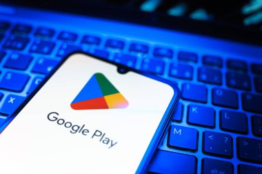 Prag, Çek Cumhuriyeti - 08 19 2025: Google Play logosunu gösteren klavyenin üzerinde duran bir cep telefonunun yakından görüntüsü. Google Play uygulamaları, oyunları ve dijital içeriği indirmek için bir platformdur.