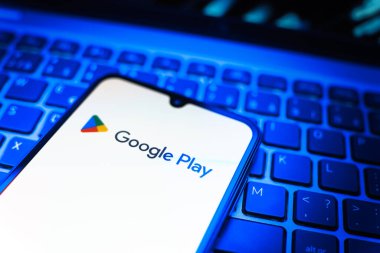 Prag, Çek Cumhuriyeti - 08 19 2025: Google Play logosunu gösteren klavyenin üzerinde duran bir cep telefonunun yakından görüntüsü. Google Play uygulamaları, oyunları ve dijital içeriği indirmek için bir platformdur.