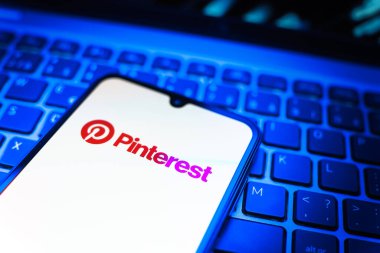 Prag, Çek Cumhuriyeti - 08 19 2025: Pinterest logosunu gösteren klavyenin üzerinde duran cep telefonunun yakından görüntüsü. Pinterest fikirleri görsel olarak keşfetmek ve kaydetmek için bir platformdur..