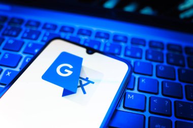 Prag, Çek Cumhuriyeti - 08 19 2025: Google Translate logosunu gösteren klavyenin üzerinde duran cep telefonunun yakından görüntüsü. Google Çevirisi metni ve konuşmayı diller arası çevirmek için bir platformdur..