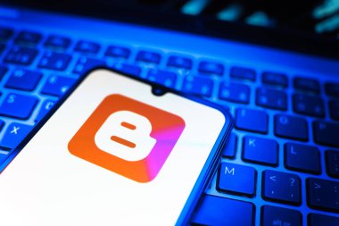 Prag, Çek Cumhuriyeti - 08 19 2025: Klavyenin üzerinde duran ve Blogger logosunu gösteren cep telefonunun yakından görüntüsü. Blogger blog oluşturma ve yayınlama için bir platformdur.