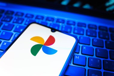 Prag, Çek Cumhuriyeti - 08 19 2025: Google Photos logosunu gösteren klavyenin üzerinde duran cep telefonunun yakından görüntüsü. Google Fotoğrafları fotoğraf ve videoları saklamak ve düzenlemek için bir platformdur.
