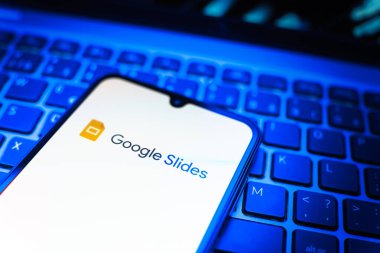 Prag, Çek Cumhuriyeti - 08 19 2025: Google Slides logosunu gösteren klavyenin üzerinde duran cep telefonunun yakından görüntüsü. Google Slides sunumlar ve slayt gösterileri oluşturmak için bir platformdur.