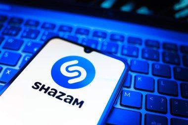 Prag, Çek Cumhuriyeti - 08 19 2025: Klavyede duran ve Shazam logosunu gösteren bir cep telefonunun yakından görüntüsü. Shazam şarkıları ve müzik parçalarını tanımlamak için bir uygulamadır.