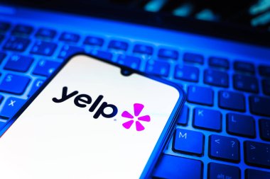 Prag, Çek Cumhuriyeti - 08 19 2025: Klavyede duran ve Yelp logosunu gösteren bir cep telefonunun yakından görüntüsü. Yelp yerel işletmeleri bulmak ve incelemek için bir platformdur.