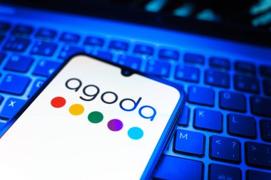 Prag, Çek Cumhuriyeti - 08 19 2025: Cep telefonunun klavyede duran ve Agoda logosunu gösteren yakın plan görüntüsü. Agoda, otelleri ve seyahat yerlerini ayırtmak için bir platform..