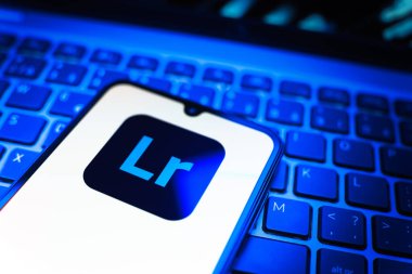 Prag, Çek Cumhuriyeti - 08 19 2025: Klavyede duran ve Lightroom logosunu gösteren cep telefonunun yakından görüntüsü. Lightroom fotoğraf düzenleme ve yönetim için bir yazılımdır..