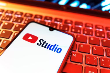 Prag, Çek Cumhuriyeti - 08 19 2025: Youtube Stüdyo logosunu gösteren klavyenin üzerinde duran cep telefonunun yakından görüntüsü. Youtube Studio YouTube kanallarını yönetmek ve analiz etmek için bir platformdur.