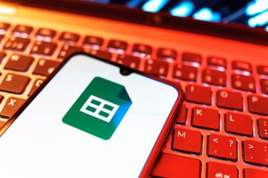 Prag, Çek Cumhuriyeti - 08 19 2025: Google Sheets logosunu gösteren klavyenin üzerinde duran cep telefonunun yakından görüntüsü. Google Sayfalar tablo oluşturmak ve yönetmek için bir platformdur.