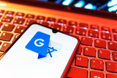 Prag, Çek Cumhuriyeti - 08 19 2025: Google Translate logosunu gösteren klavyenin üzerinde duran cep telefonunun yakından görüntüsü. Google Çevirisi metni ve konuşmayı diller arası çevirmek için bir platformdur..
