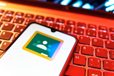 Prag, Çek Cumhuriyeti - 08 19 2025: Google Sınıfı logosunu gösteren klavyenin üzerinde duran cep telefonunun yakından görüntüsü. Google Sınıfı, sınıfları ve eğitim içeriğini yönetmek için bir platformdur.