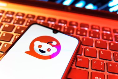 Prag, Çek Cumhuriyeti - 08 19 2025: Bir klavyenin üzerinde duran ve Reddit logosunu gösteren cep telefonunun yakından görüntüsü. Reddit tartışma, haber ve toplum içeriği için bir platformdur.