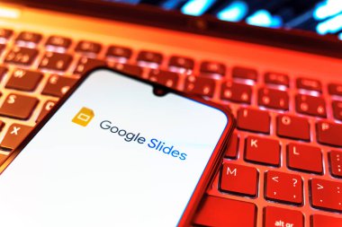 Prag, Çek Cumhuriyeti - 08 19 2025: Google Slides logosunu gösteren klavyenin üzerinde duran cep telefonunun yakından görüntüsü. Google Slides sunumlar ve slayt gösterileri oluşturmak için bir platformdur.