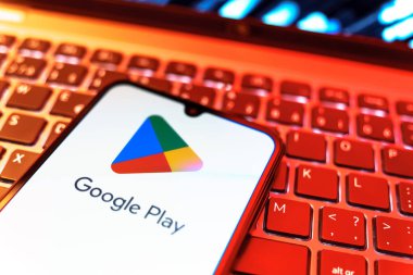 Prag, Çek Cumhuriyeti - 08 19 2025: Google Play logosunu gösteren klavyenin üzerinde duran bir cep telefonunun yakından görüntüsü. Google Play uygulamaları, oyunları ve dijital içeriği indirmek için bir platformdur.
