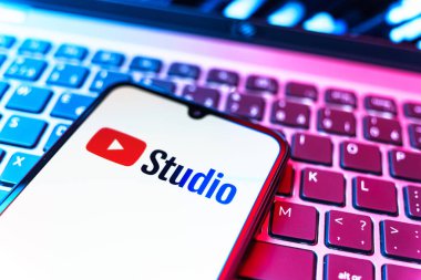 Prag, Çek Cumhuriyeti - 08 19 2025: Youtube Stüdyo logosunu gösteren klavyenin üzerinde duran cep telefonunun yakından görüntüsü. Youtube Studio YouTube kanallarını yönetmek ve analiz etmek için bir platformdur.