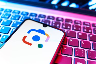 Prag, Çek Cumhuriyeti - 08 19 2025: Google Lens logosunu gösteren klavyenin üzerinde duran cep telefonunun yakından görüntüsü. Google Lens, resimlerdeki görsel arama ve bilgi için kullanılan bir araçtır..