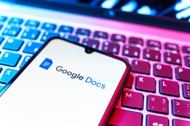 Prag, Çek Cumhuriyeti - 08 19 2025: Google Docs logosunu gösteren klavyenin üzerinde duran cep telefonunun yakından görüntüsü. Google Docs metin belgeleri oluşturmak ve düzenlemek için bir platformdur.