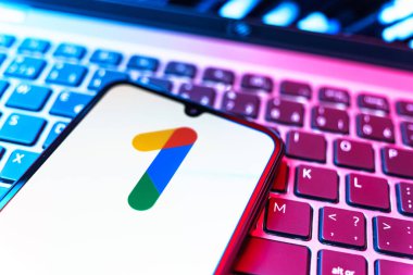 Prag, Çek Cumhuriyeti - 08 19 2025: Bir klavyenin üzerinde duran ve Google One logosunu gösteren cep telefonunun yakından görüntüsü. Google 1 bulut depolama ve abonelik hizmetleri için bir platformdur.