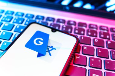Prag, Çek Cumhuriyeti - 08 19 2025: Google Translate logosunu gösteren klavyenin üzerinde duran cep telefonunun yakından görüntüsü. Google Çevirisi metni ve konuşmayı diller arası çevirmek için bir platformdur..