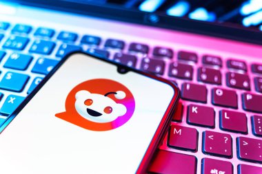Prag, Çek Cumhuriyeti - 08 19 2025: Bir klavyenin üzerinde duran ve Reddit logosunu gösteren cep telefonunun yakından görüntüsü. Reddit tartışma, haber ve toplum içeriği için bir platformdur.