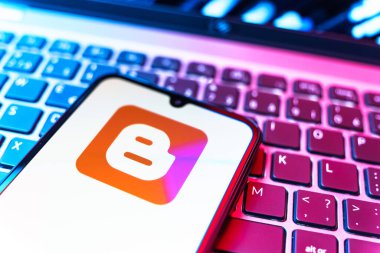 Prag, Çek Cumhuriyeti - 08 19 2025: Klavyenin üzerinde duran ve Blogger logosunu gösteren cep telefonunun yakından görüntüsü. Blogger blog oluşturma ve yayınlama için bir platformdur.