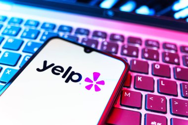 Prag, Çek Cumhuriyeti - 08 19 2025: Klavyede duran ve Yelp logosunu gösteren bir cep telefonunun yakından görüntüsü. Yelp yerel işletmeleri bulmak ve incelemek için bir platformdur.