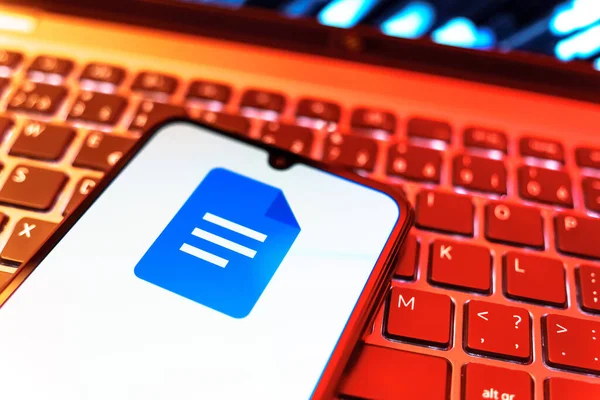 Prag, Çek Cumhuriyeti - 08 19 2025: Google Docs logosunu gösteren klavyenin üzerinde duran cep telefonunun yakından görüntüsü. Google Docs metin belgeleri oluşturmak ve düzenlemek için bir platformdur.